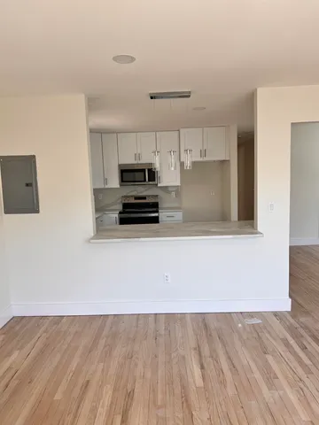 a kitchen with kitchen island a stove top oven a sink and white cabinets