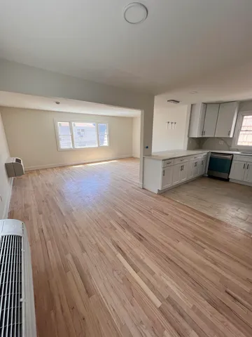 an empty room with wooden floor and window