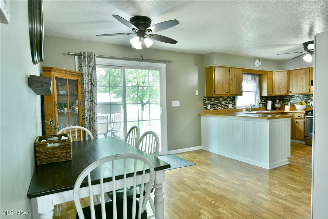 2847 Selkirk Bush Road Warren, OH 44481 - Photo 13 of 47 Kitchen featuring a ceiling fan, a textured ceiling, tasteful backsplash, light wood-style floors, and a peninsula