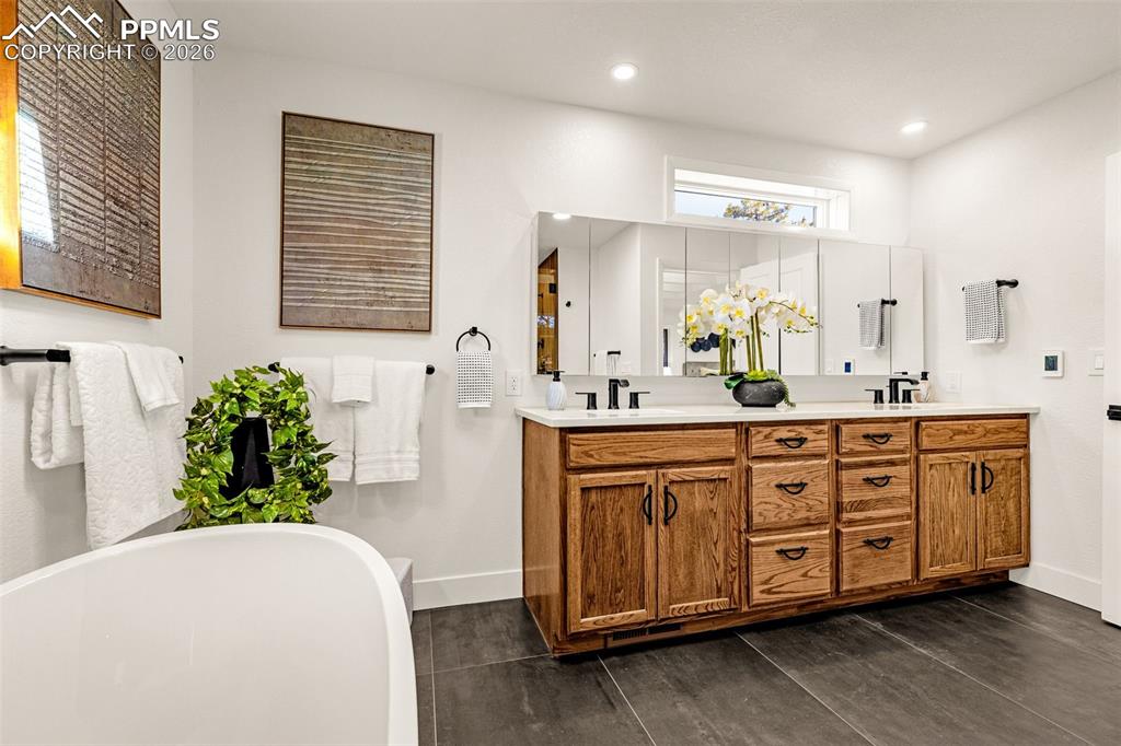 26 Leaming Road Colorado Springs, CO 80906 - Photo 30 of 45 a spacious bathroom with double vanity a mirror a bathtub and a shower