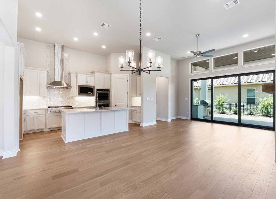 205 Indigo Lane Georgetown, TX 78628 - Photo 31 of 33 a large kitchen with white cabinets and wooden floor