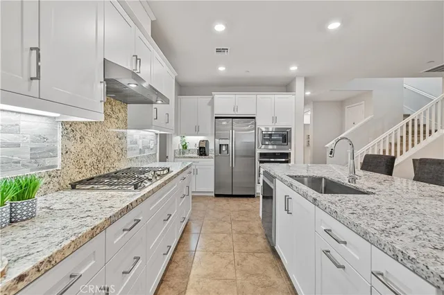 a kitchen with stainless steel appliances granite countertop a sink stove and refrigerator