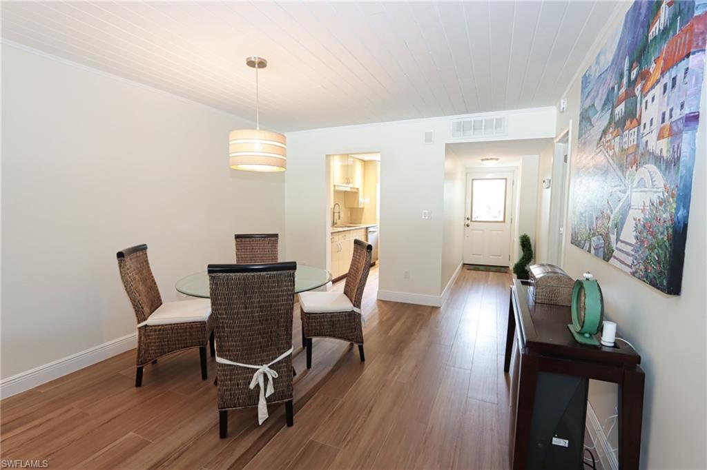 820 Ketch Drive, Unit 3 Naples, FL 34103 - Photo 8 of 19 a dining room with wooden floor a chandelier a wooden table and chairs