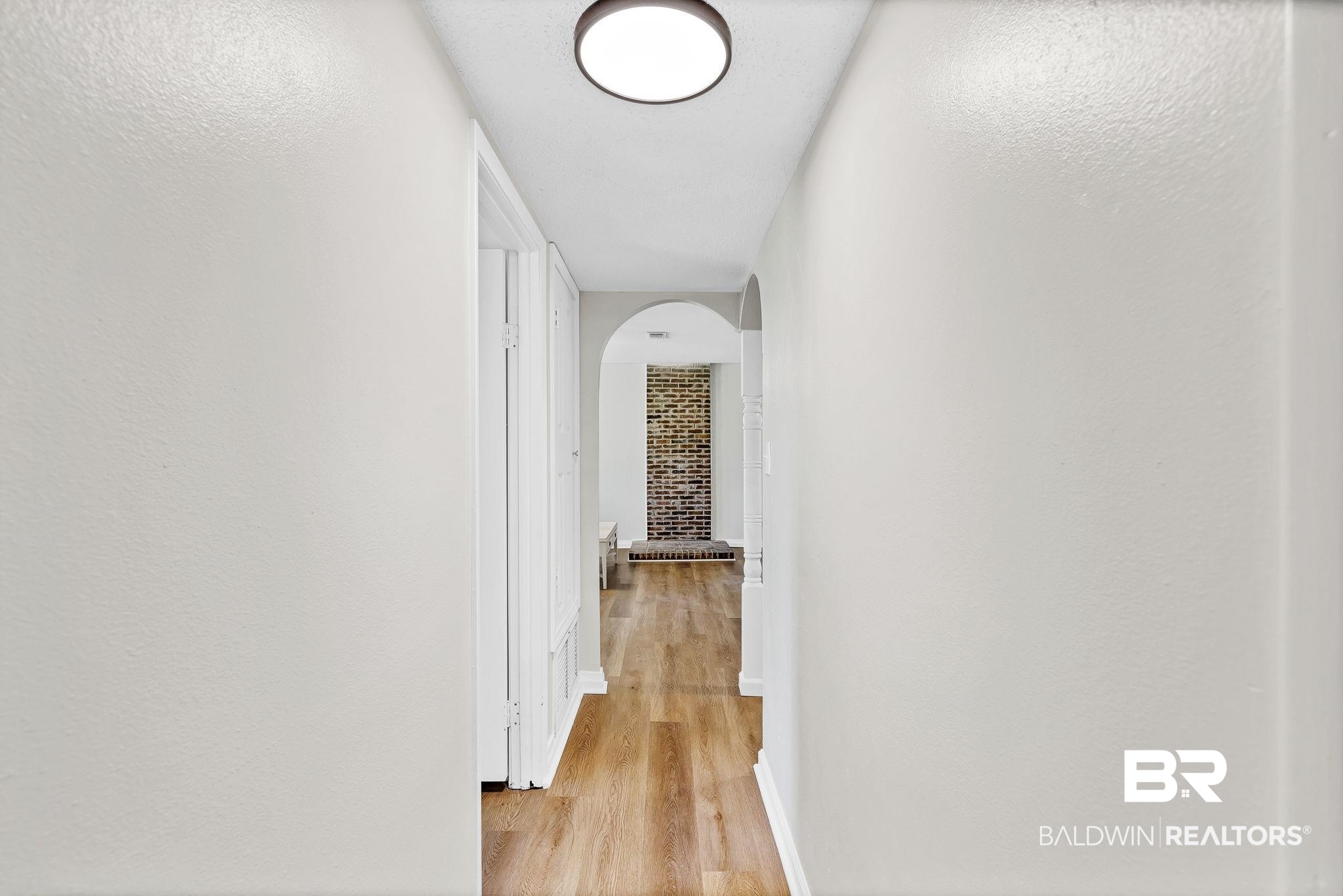 11964 Stroh Road Daphne, AL 36527 - Photo 29 of 58 Corridor featuring light wood-style flooring, arched walkways, and baseboards