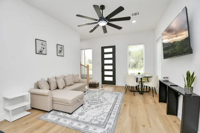 a living room with furniture a flat screen tv and a large window