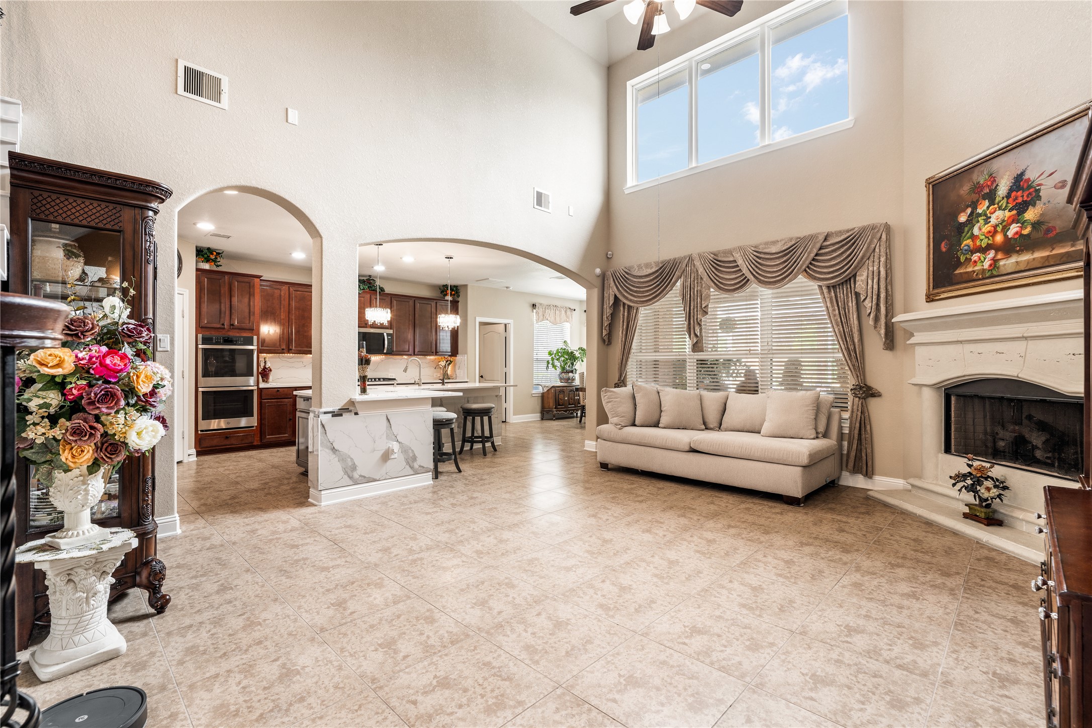 5802 Layton Meadows Lane Spring, TX 77379 - Photo 7 of 42 Living room open-concept with kitchen arch. Two-story windows flooding the space, arched doorway to kitchen, fireplace, and marble island all in frame.