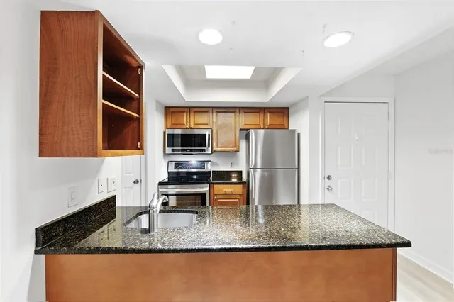a kitchen with stainless steel appliances granite countertop a sink a refrigerator and a granite counter tops