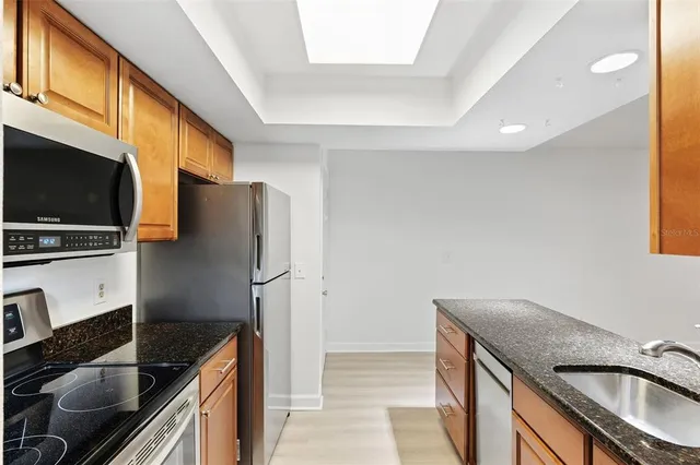 a kitchen with stainless steel appliances granite countertop a sink a stove and a refrigerator