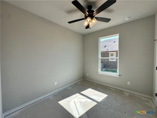 an empty room with chandelier fan and windows
