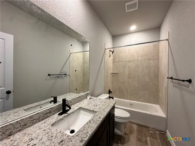 a bathroom with a granite countertop sink a toilet and shower