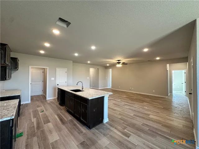 a view of a kitchen counter top space with stainless steel appliances wooden floor and living room view