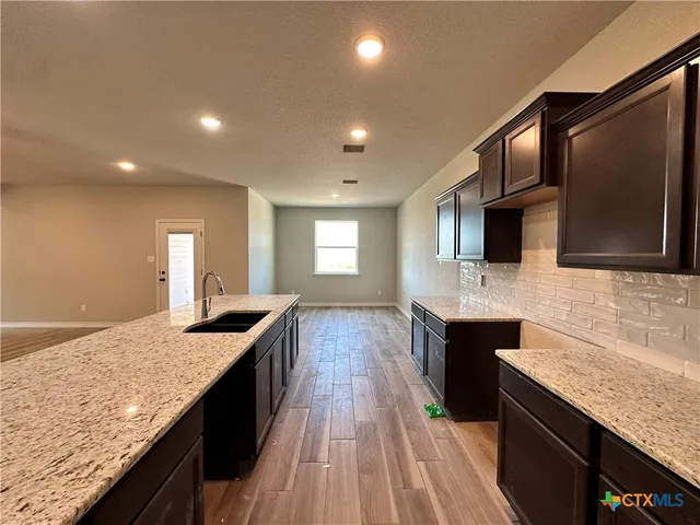 a kitchen with granite countertop kitchen island stainless steel appliances a sink stove top oven and microwave