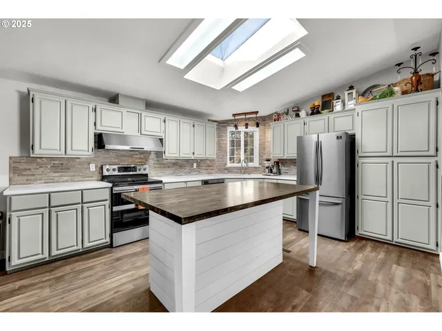 a kitchen with granite countertop a refrigerator stove top oven and sink