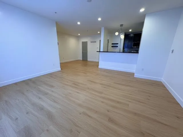 a view of a big room with wooden floor and kitchen