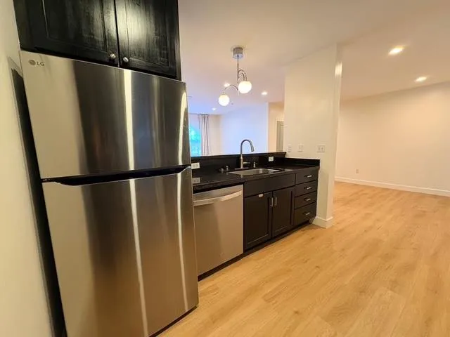 a kitchen with a sink a refrigerator and a stove top oven