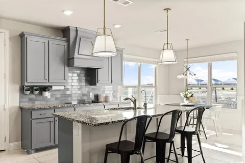 a kitchen with stainless steel appliances granite countertop a dining table chairs sink and stove