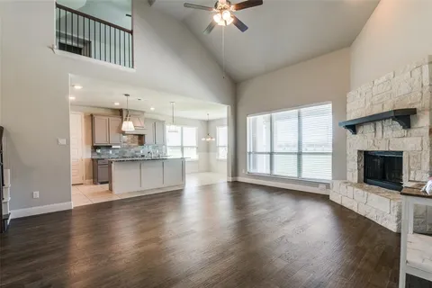 a view of an empty room with wooden floor and a kitchen