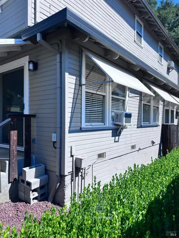 a view of a house with potted plants and a table and chairs