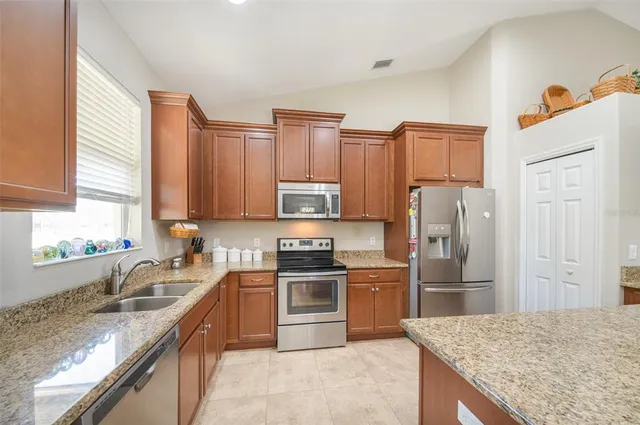 a kitchen with stainless steel appliances granite countertop a sink stove refrigerator and cabinets