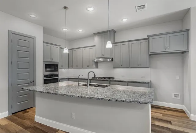 a kitchen with kitchen island granite countertop a sink a counter space stainless steel appliances and cabinets