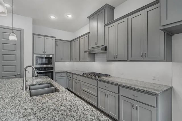 a kitchen with granite countertop a sink stove and cabinets