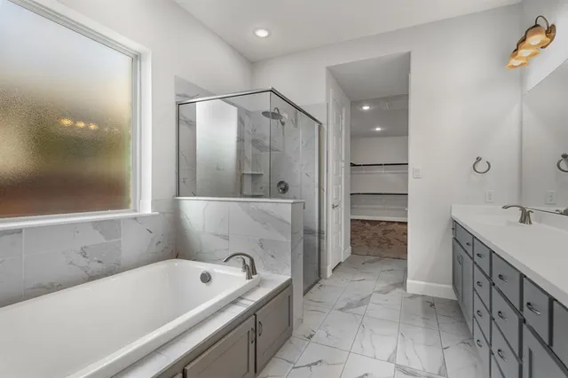 a bathroom with a tub a sink and a large mirror