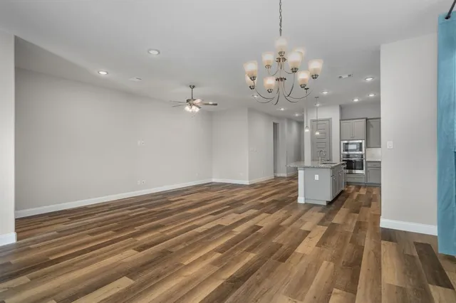 a view of a big room with wooden floor and a kitchen