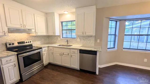 a kitchen with granite countertop wooden floors and white stainless steel appliances