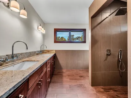 a bathroom with a granite countertop sink a mirror and shower
