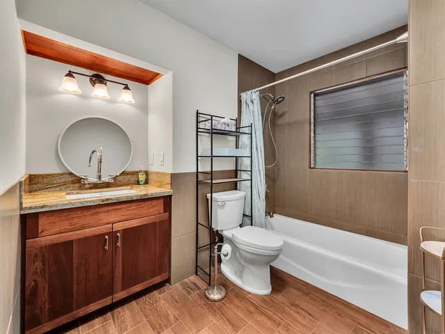 a bathroom with a granite countertop toilet a sink and a mirror