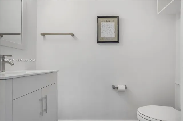 a bathroom with a toilet sink vanity and mirror