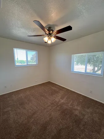 an empty room with windows and fan