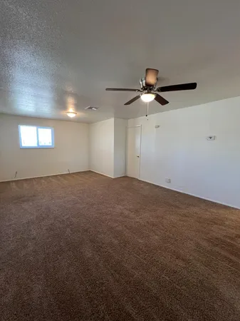 an empty room with ceiling fan and window
