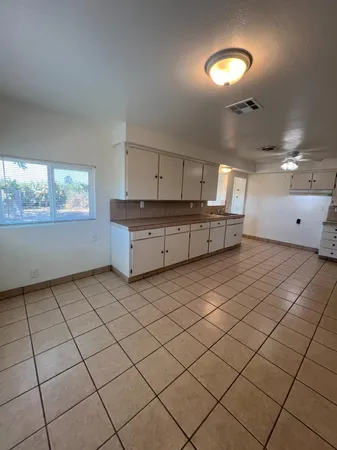 a large white kitchen with a large window and cabinets