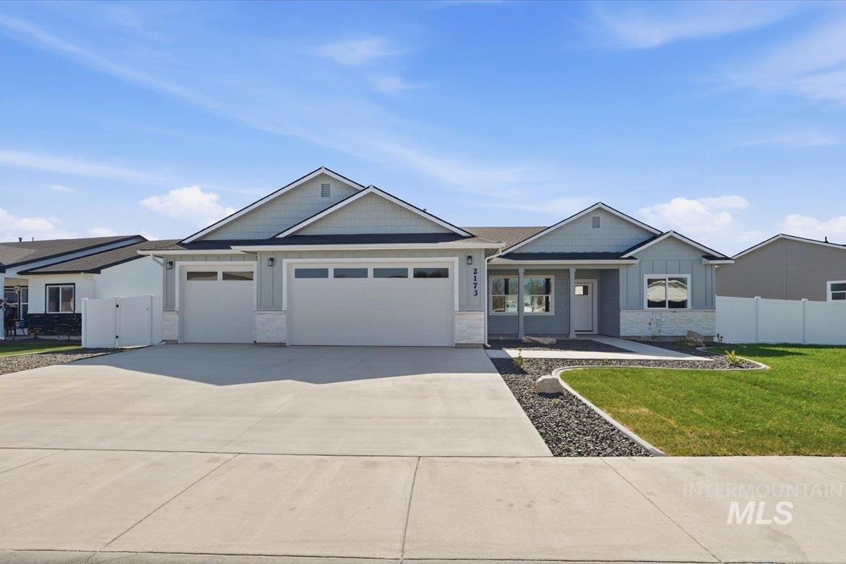 2173 Austin Way Fruitland, ID 83619 - Photo 1 of 28 Craftsman-style house with stone siding, driveway, an attached garage, board and batten siding, and a porch