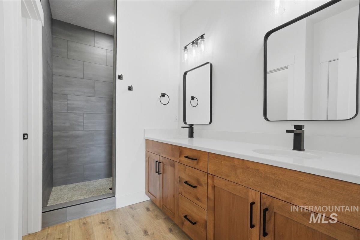 2173 Austin Way Fruitland, ID 83619 - Photo 19 of 28 Full bath featuring double vanity, light wood-type flooring, and tiled shower