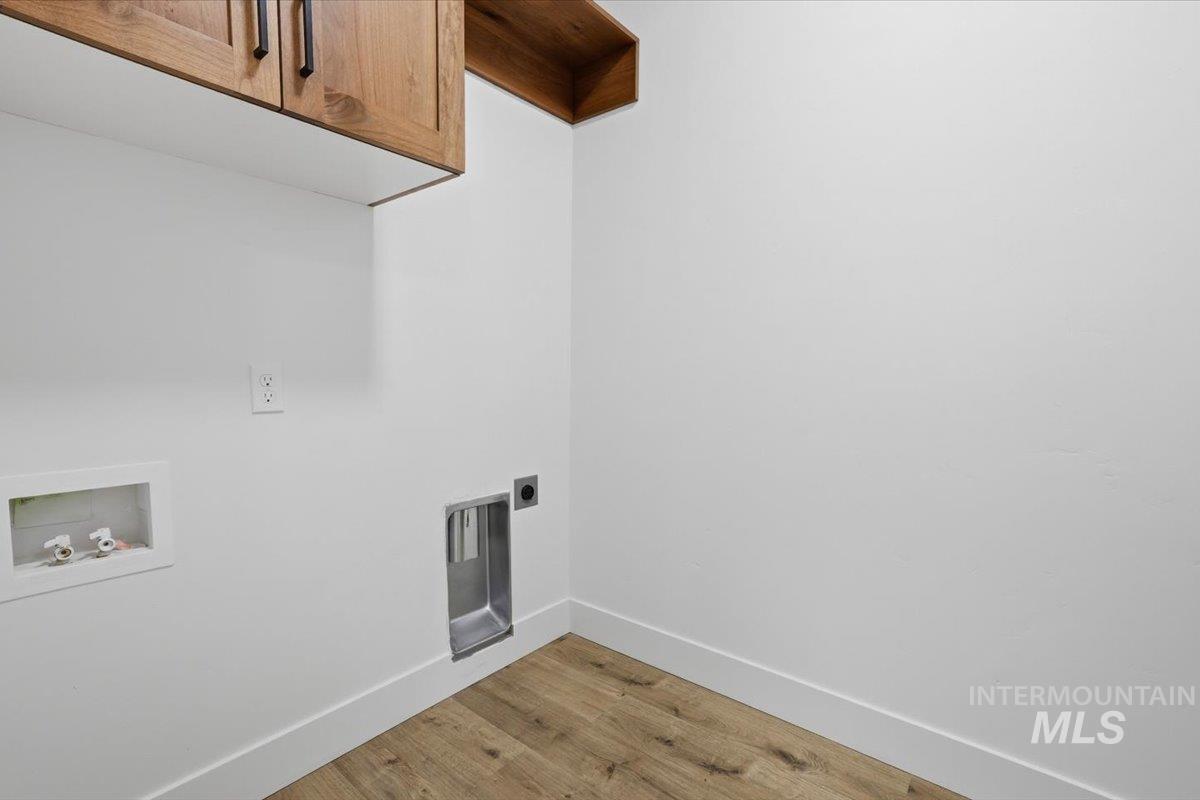 2173 Austin Way Fruitland, ID 83619 - Photo 22 of 28 Laundry area with light wood-type flooring, hookup for a washing machine, cabinet space, and hookup for an electric dryer