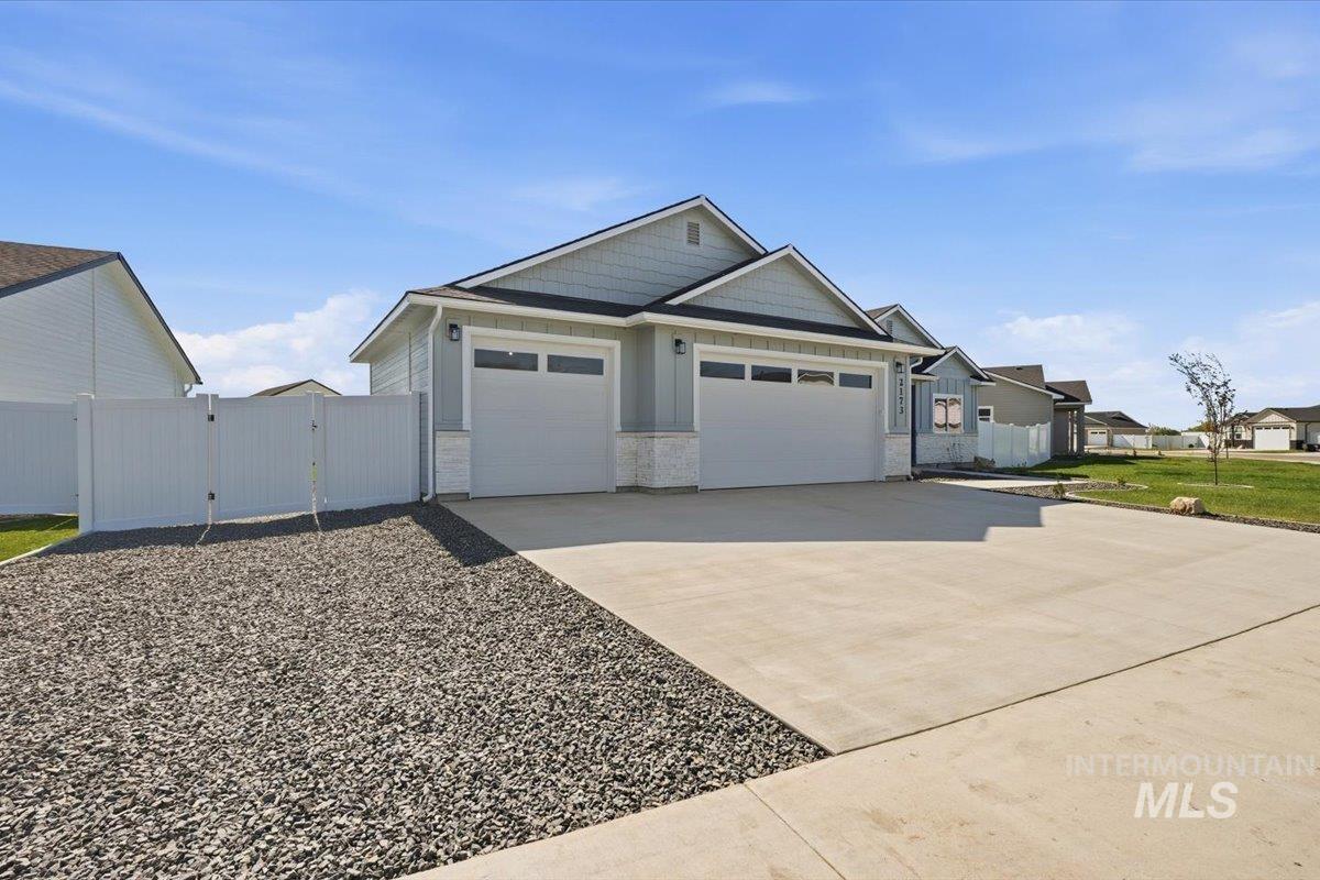 2173 Austin Way Fruitland, ID 83619 - Photo 3 of 28 View of front facade with a gate, concrete driveway, an attached garage, and stone siding