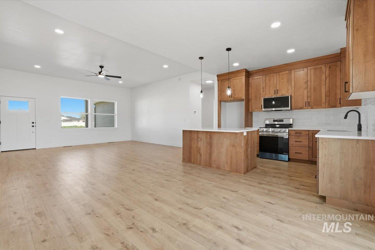 2173 Austin Way Fruitland, ID 83619 - Photo 27 of 28 Kitchen featuring open floor plan, a center island, stainless steel appliances, wood finish cabinets, and decorative backsplash