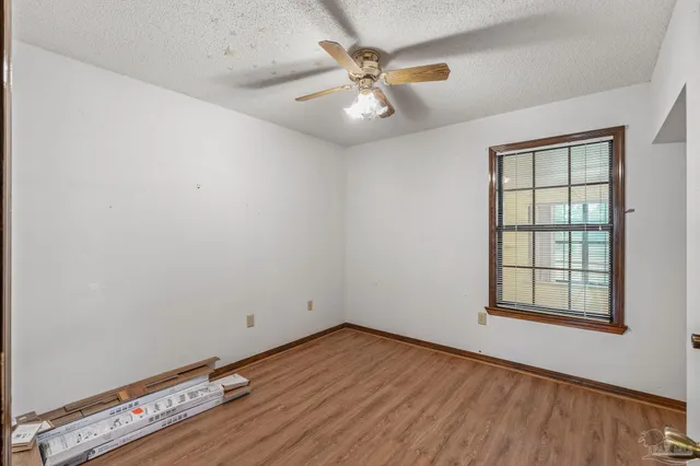 an empty room with wooden floor chandelier fan and windows
