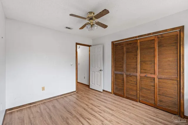an empty room with wooden floor a ceiling fan and windows