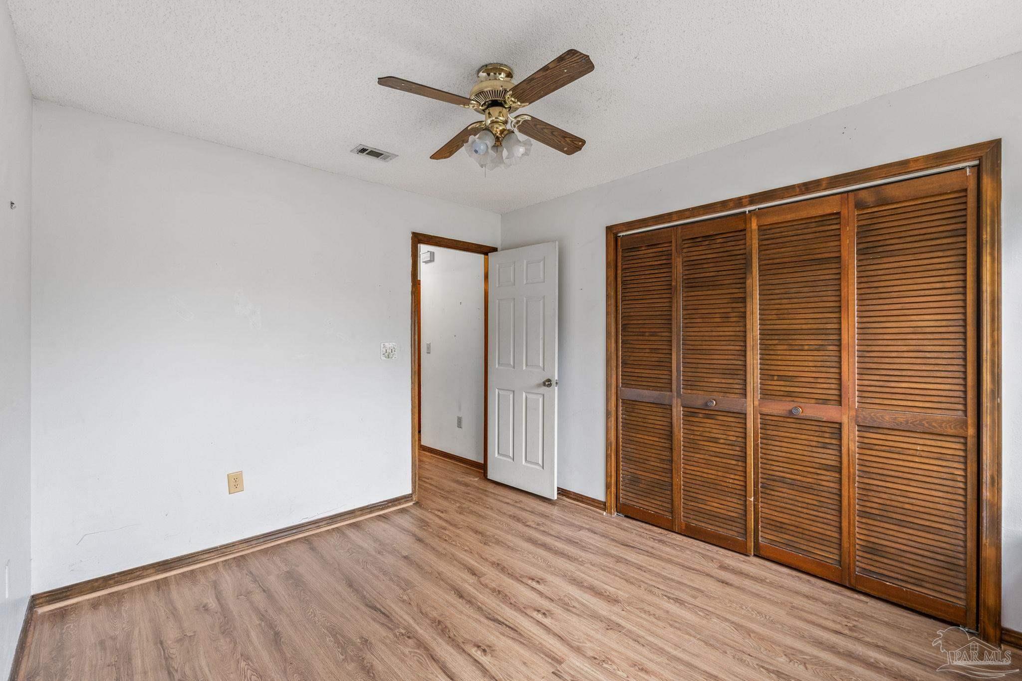 426 Brown Place Crestview, FL 32539 - Photo 31 of 40 an empty room with wooden floor a ceiling fan and windows