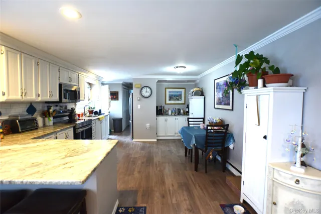 a kitchen with stainless steel appliances kitchen island granite countertop a refrigerator a stove top oven a dining table and chairs with wooden floor