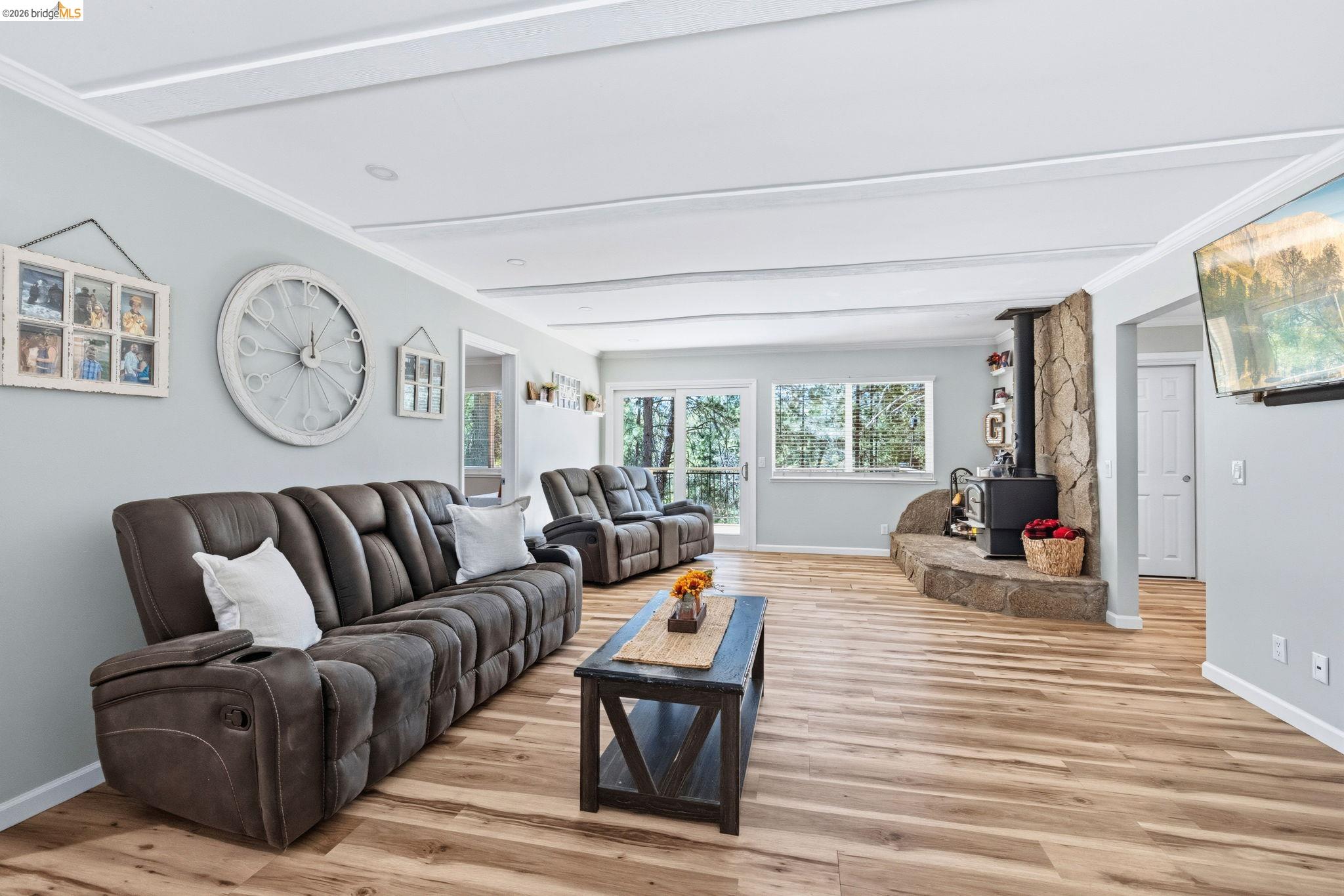 19059 Raboul Court Groveland, CA 95321 - Photo 5 of 21 Spacious living area featuring wood-finish flooring, a stone fireplace with a hearth, and substantial natural light from multiple windows