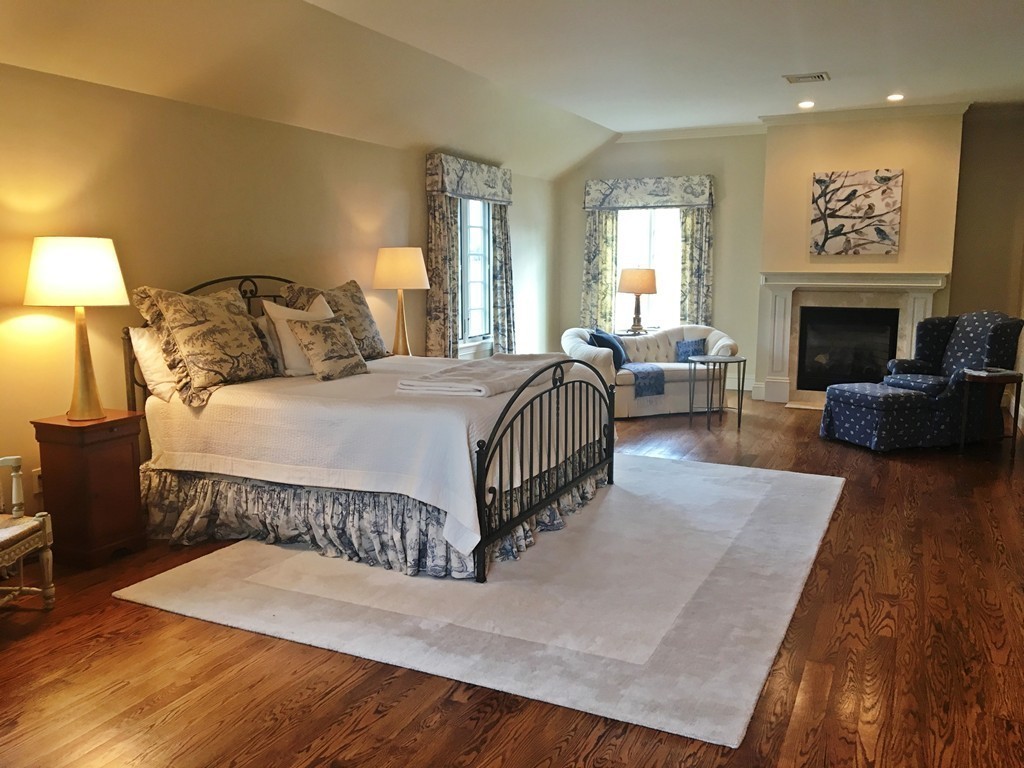 77 Cliff Road Wellesley, MA 02481 - Photo 13 of 29 a spacious bedroom with a bed a couch and a fireplace