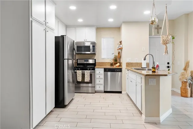 a kitchen with stainless steel appliances kitchen island granite countertop a refrigerator and a sink