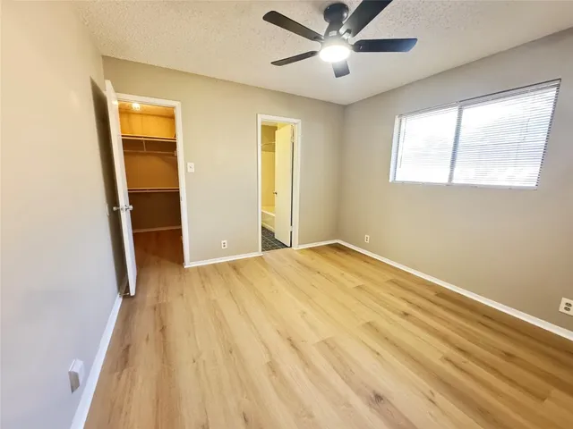 a view of empty room with wooden floor and fan