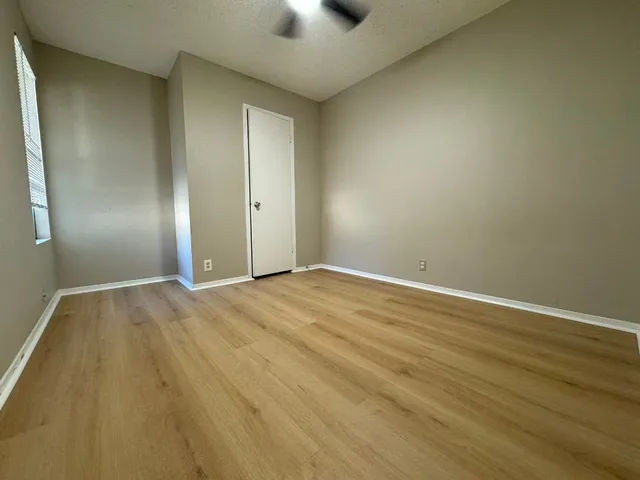 an empty room with wooden floor and windows