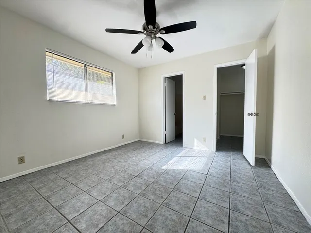 a view of an empty room with window and chandelier fan