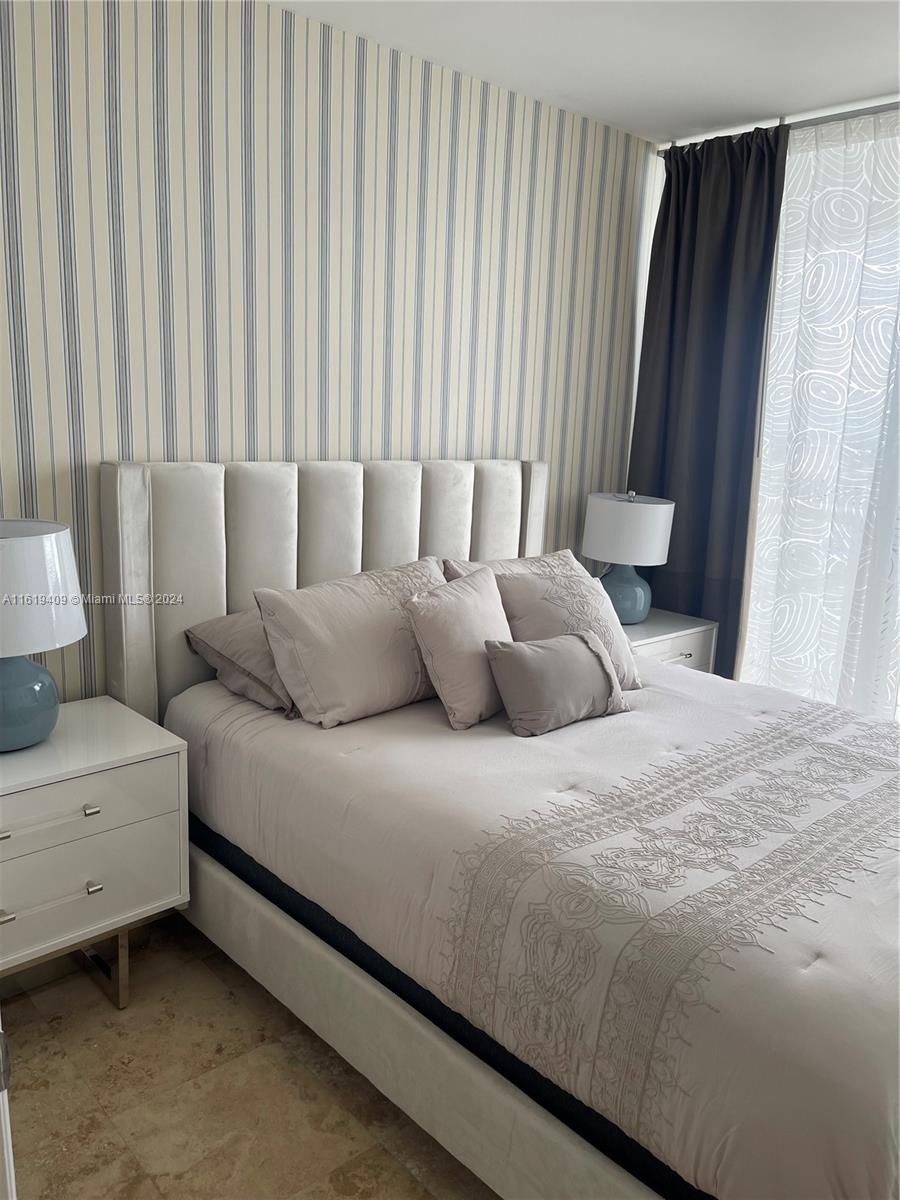 6365 Collins Avenue, Unit 2610 Miami Beach, FL 33141 - Photo 14 of 49 a large bed sitting in a bedroom next to a window and a chair